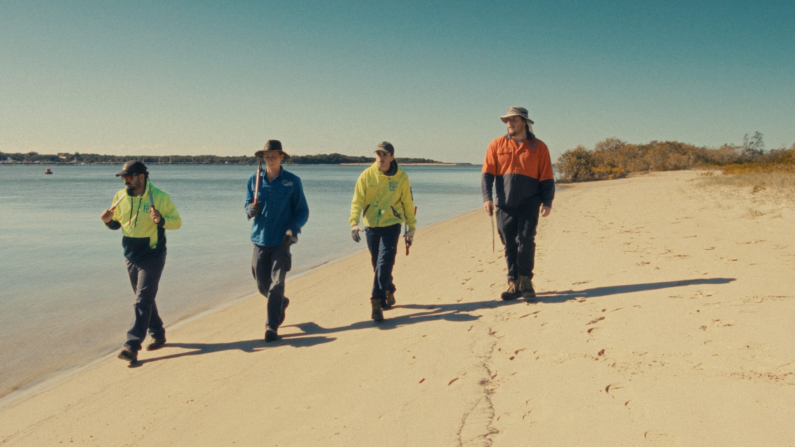 Four people in high-vis walking along a beach