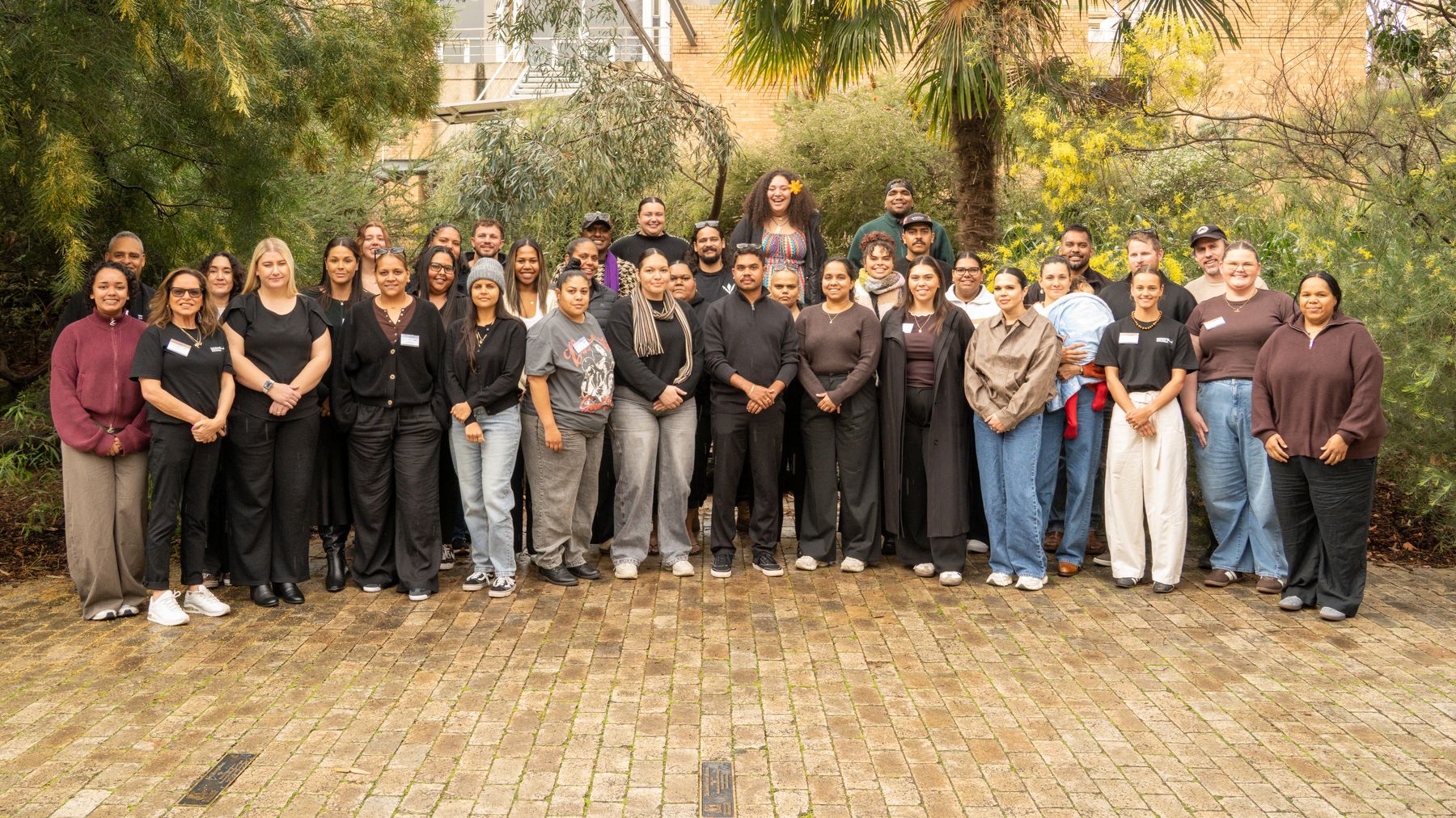 A large group gathered outdoors in a garden courtyard for a photograph